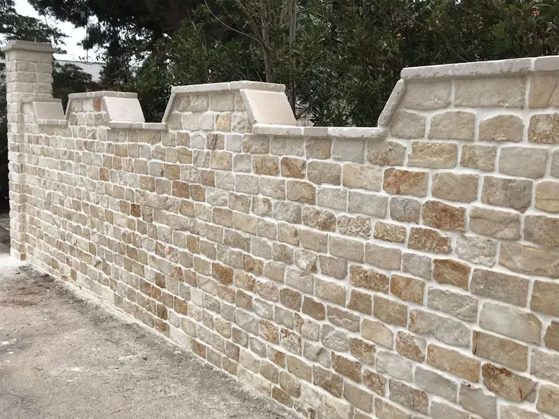 Muro di cinta rivestito in pietra con copertine