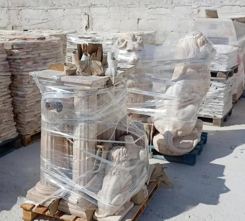 Statue di leoni e colonne in pietra imballate su pallet