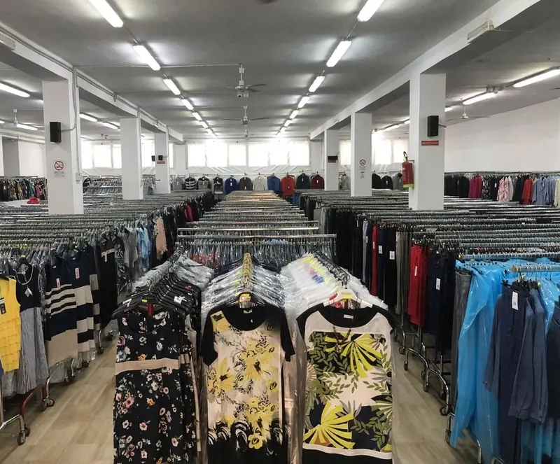 File di stender con abbigliamento in un ampio magazzino